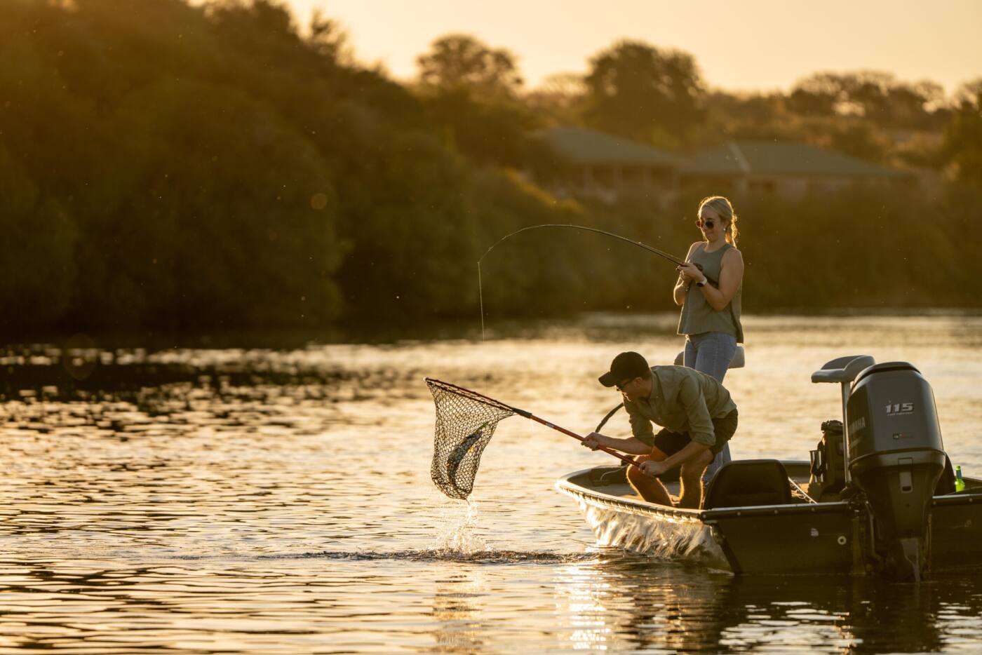 Angler landing a fish from the boat at sunrise